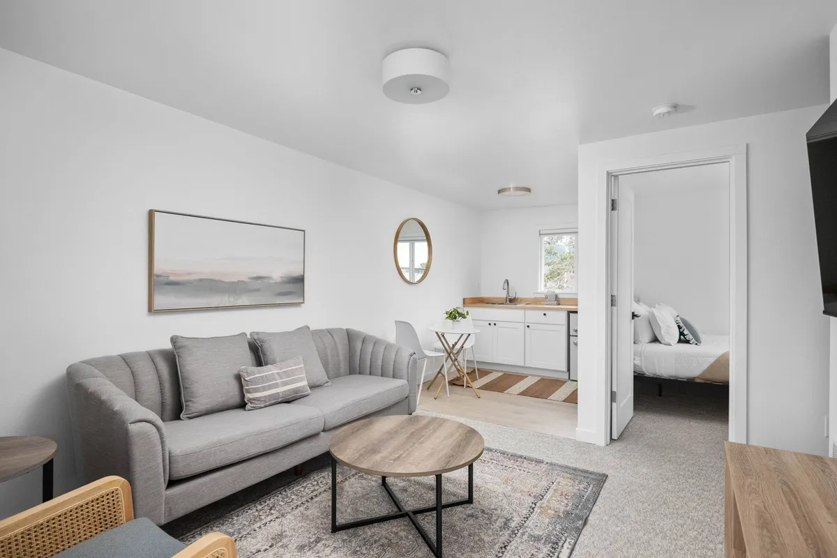 The image shows a beautifully remodeled condo interior featuring a cozy sofa, a stylish coffee table, tasteful artwork, and a large mirror, all arranged to create a welcoming space ideal for relaxing, reading, or socializing.