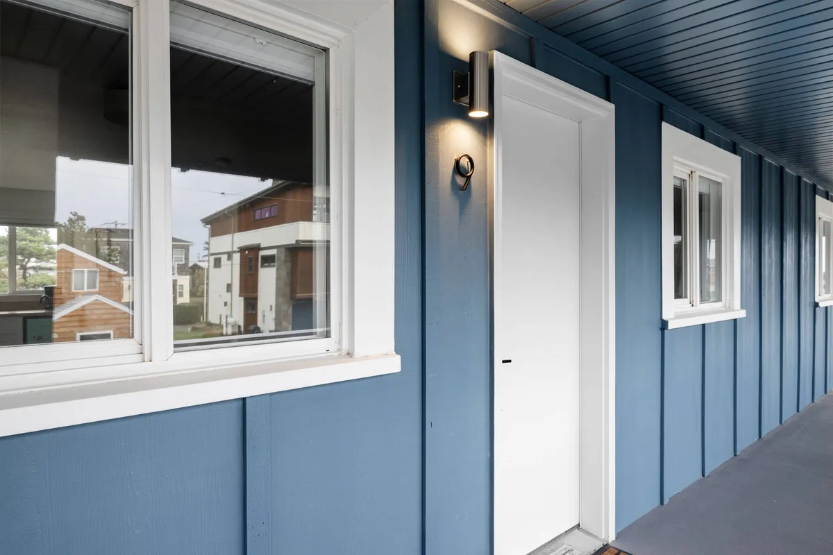 This image features the inviting blue exterior wall of the property, complemented by a crisp white door and a welcoming light fixture. The scene suggests a relaxed and approachable atmosphere, perfect for guests arriving or heading out for a romantic evening stroll.